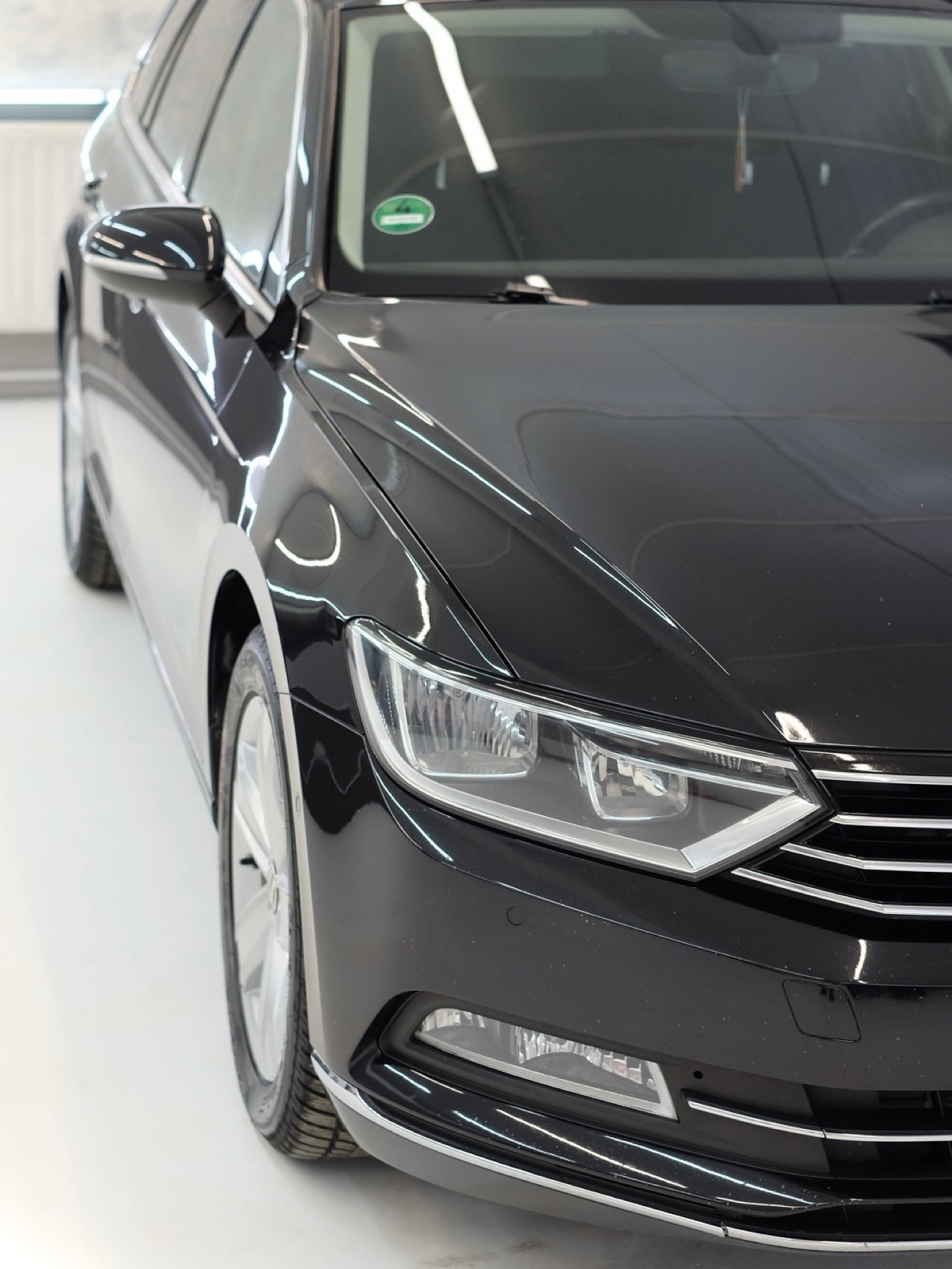 Detail prednej časti čierneho Volkswagenu Passat po leštení
